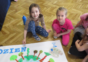 Dziewczynki przygotowują plakat z okazji Dnia Ziemi.